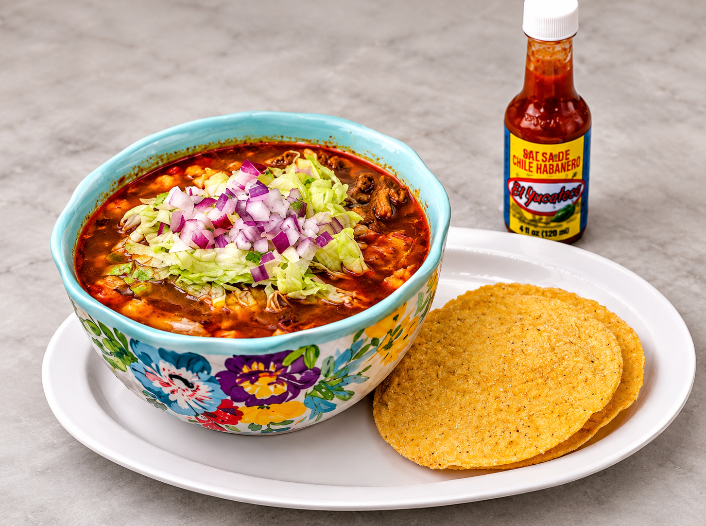 Pozole bowl with lettuce and onion, served with tostadas and hot sauce