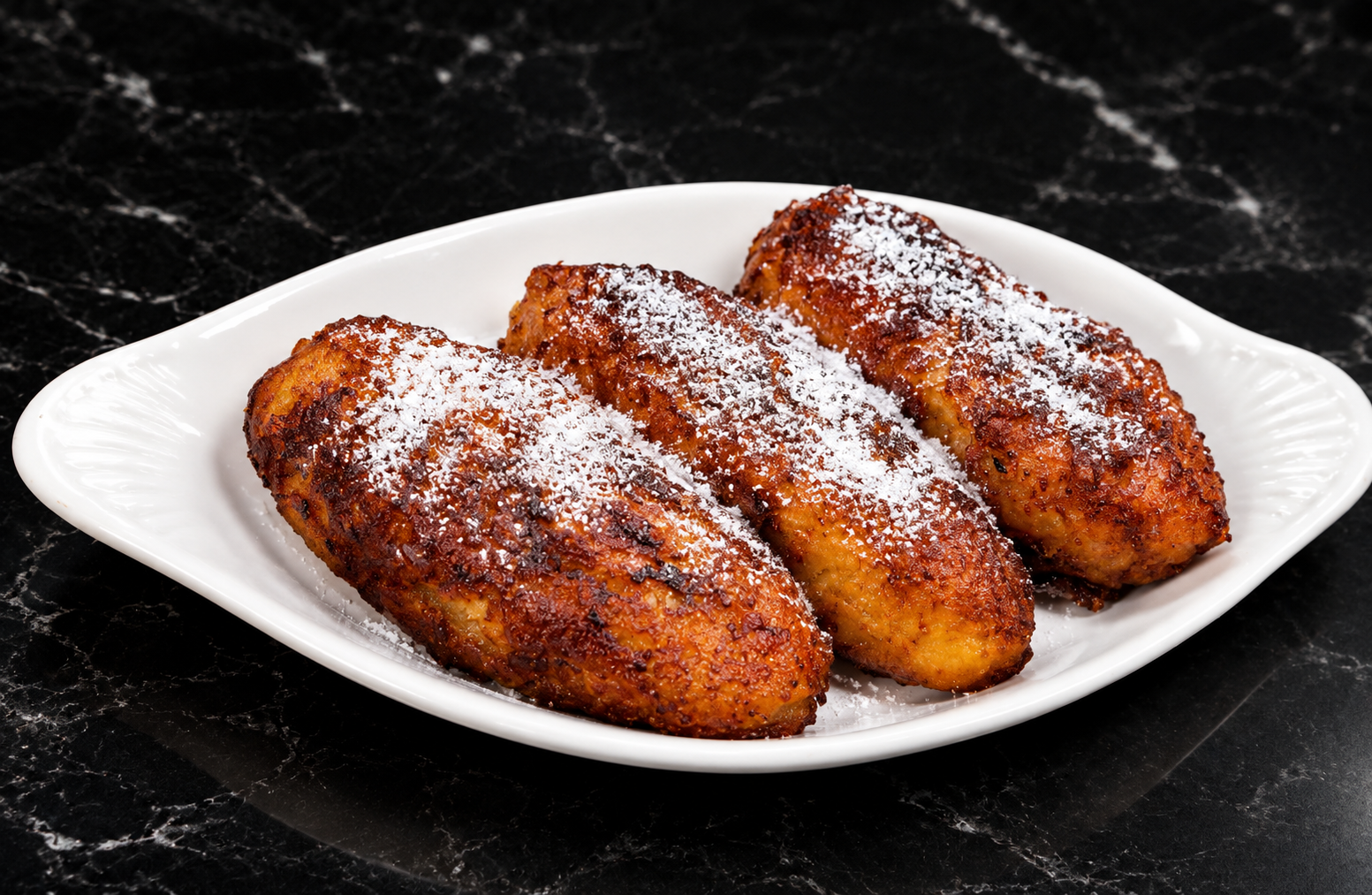Fried sweet plantains dusted with powdered cheese on a white plate