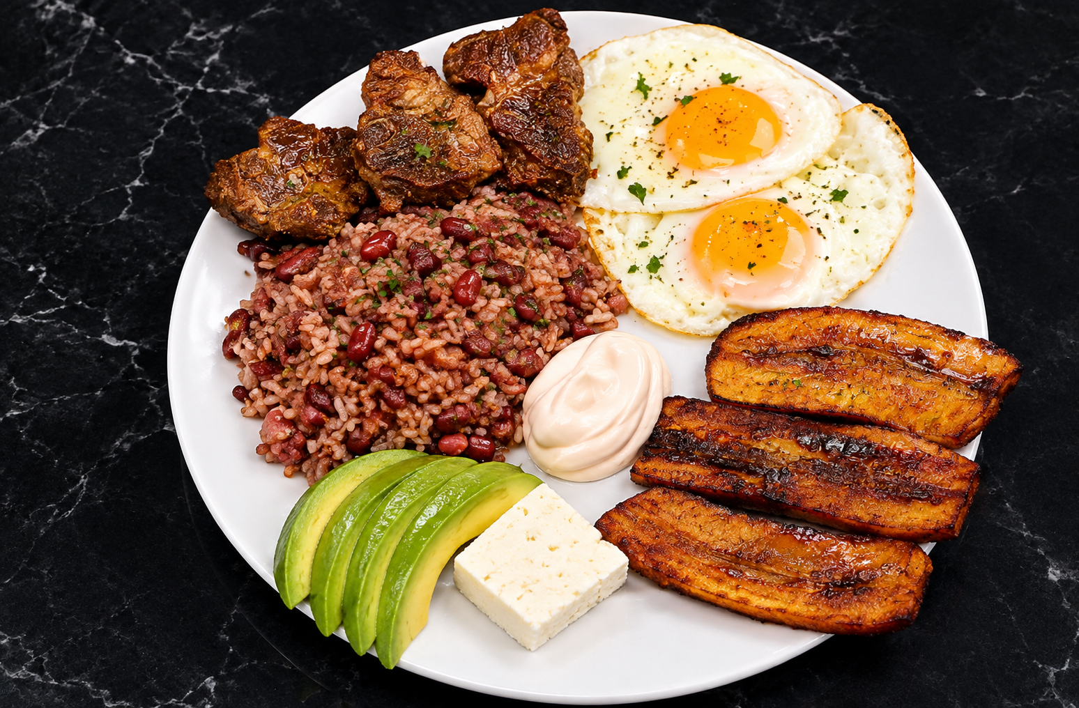 Breakfast plate with beef, fried eggs, rice and beans, avocado, cheese and sweet plantains