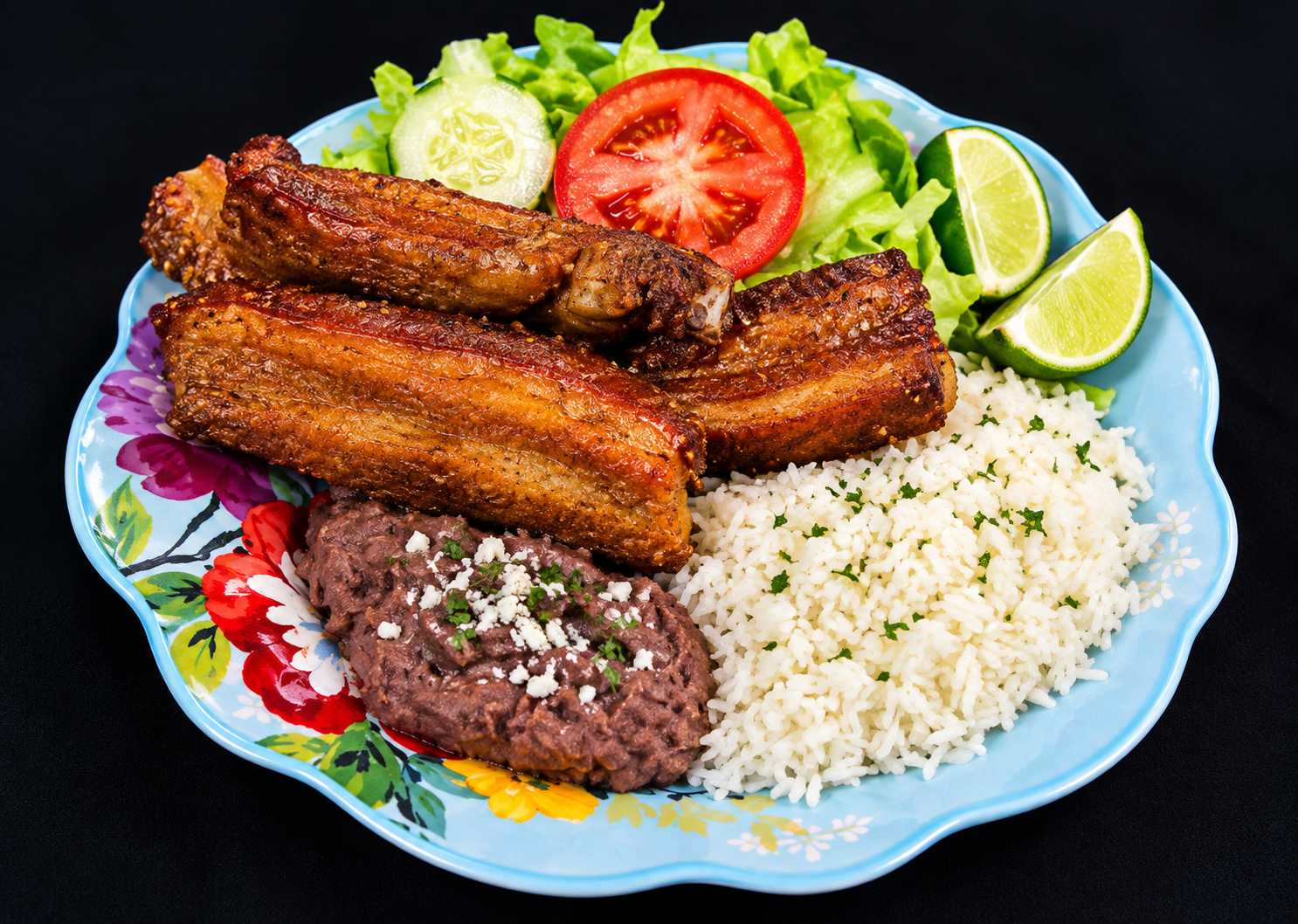 Fried pork ribs served with rice, refried beans, salad and lime